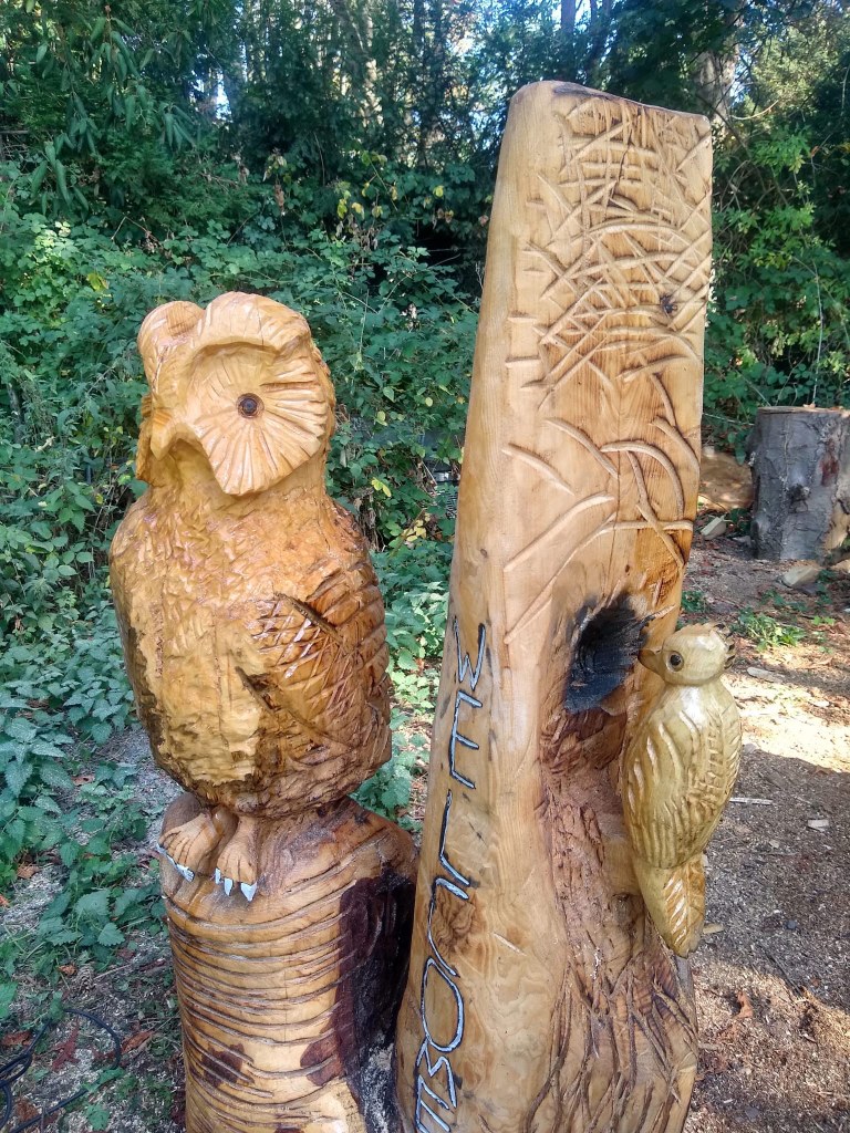 Arbeitsproben des Carving-Künstlers Norbert Weisbrod Zwei Beispiele für Carving-Kunst stehen im Park: der eine Baumstamm wurde in Form einer Eule gebracht, der andere hat die Form eines Spechts, welcher ein Loch in den Baumstamm hämmert.