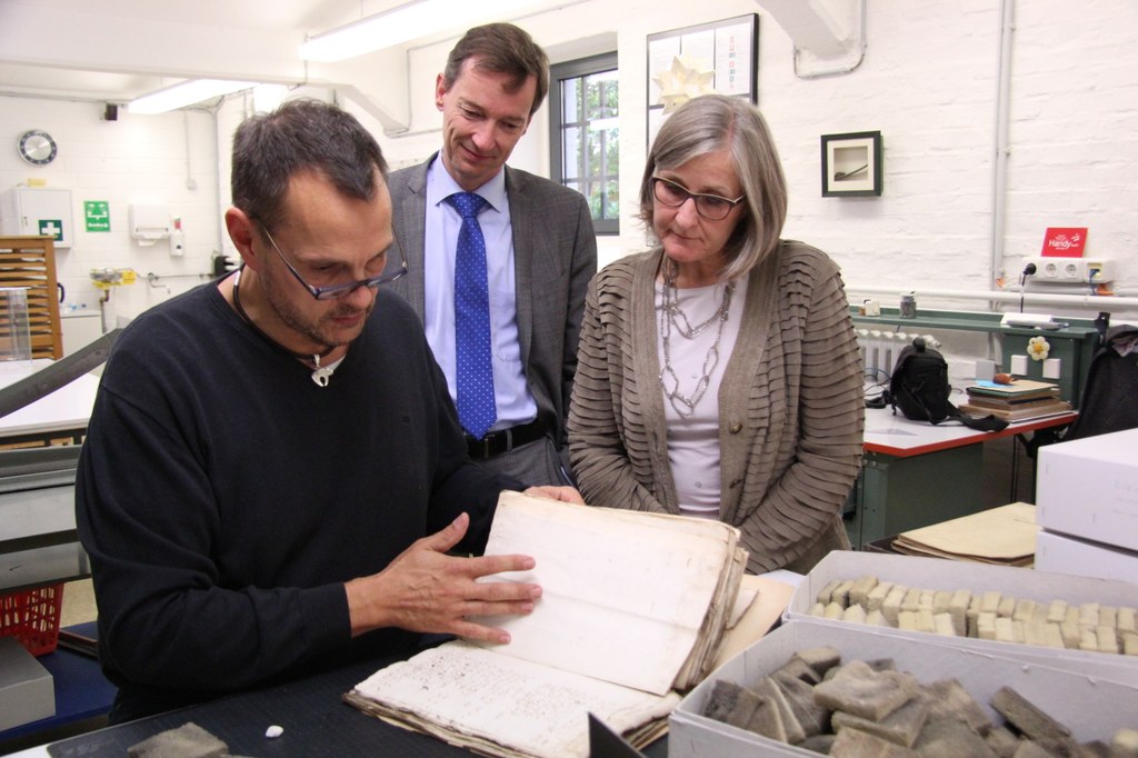 Kulturdezernentin Dr. Christiane Zangs lässt sich von Archivleiter Dr. Jens Metzdorf (m.) und Marcus Janssens, Leiter der Restaurierungswerkstatt des Stadtarchivs, die beschädigten Dokumente zeigen, die nun mit Fördermitteln des Bundes restauriert werden.