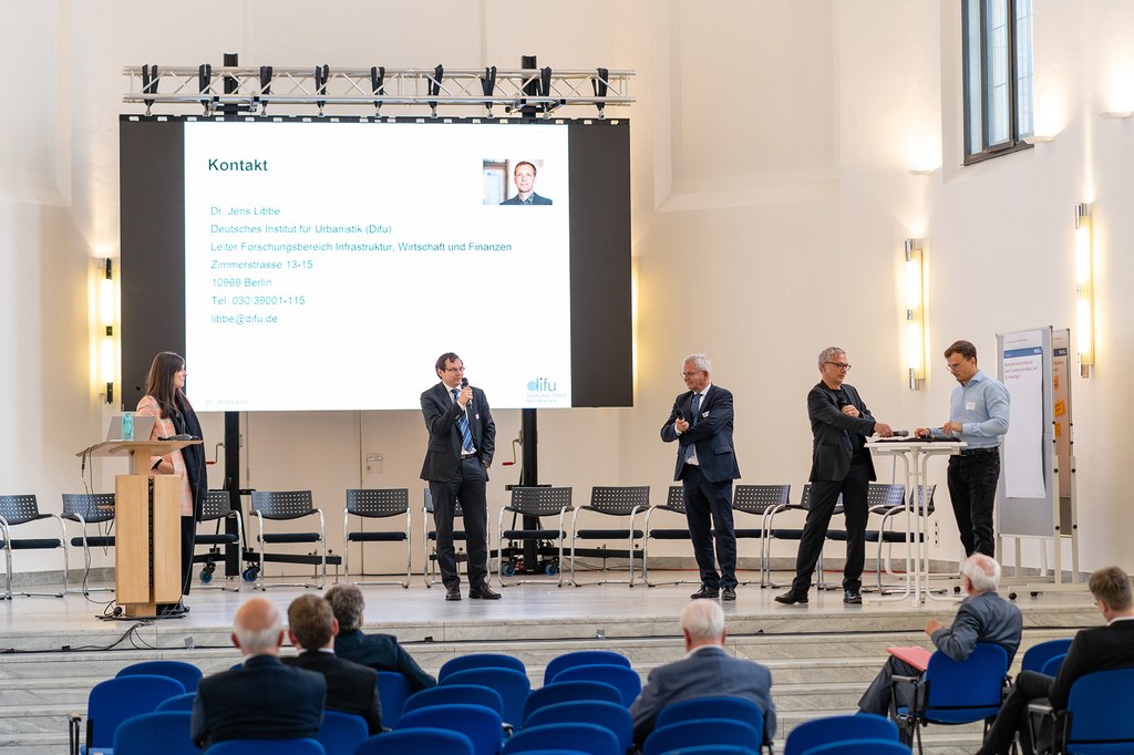 neusser-zukunftskongress-2022_14c.jpg Panel-Teilnehmer*innen stehen auf der Bühne des Zeugauses und tauschen sich aus.